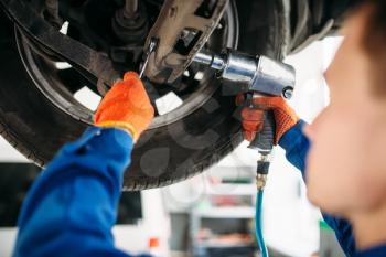 Technician with a wrench repair the suspension, car on the lift. Automobile service, vehicle maintenance
