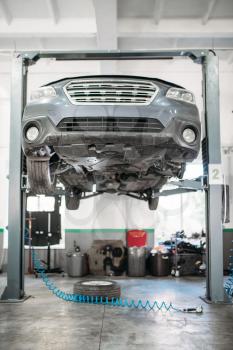 Car with removed wheel on the lift, nobody. Automobile repair, vehicle maintenance, tire service