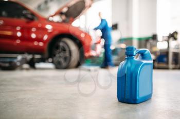 Oil canister on the floor in car service, fluid replacement. Vehicle motor maintenance, auto-service