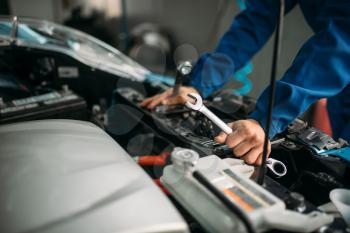 Male technician works with car engine. Auto-service, vehicle maintenance, repairman with tools