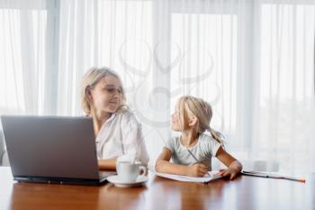 Mother uses laptop at home, child looks at her. Parent feeling, togetherness, happy family