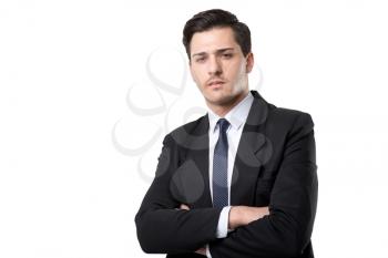 Young serious businessman in tie and black suit poses, isolated on white background