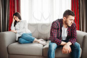 Unhappy stressed couple sitting on couch, family conflict. Unhappy man and woman in quarrel