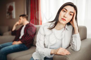 Couple sitting on couch, abuse concept. Unhappy man and woman in quarrel