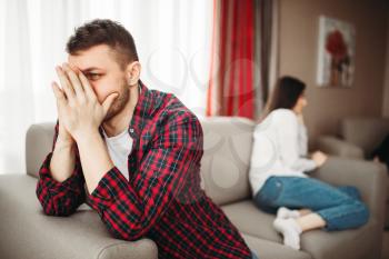 Unhappy couple sitting on couch, family conflict. Unhappy man and woman in quarrel