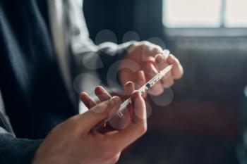 Male junkie holds syringe in hands. Drug addiction concept, addicted people