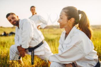 Two female karate with male instructor on training in summer field. Martial art workout outdoor, technique practice