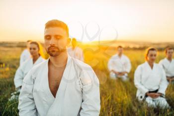Karate master on training with his group, summer field on background. Martial art school on workout outdoor, technique practice
