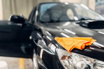 Rag on the hood of clean car with open doors, nobody. Professional dry cleaning of car on carwash service. 