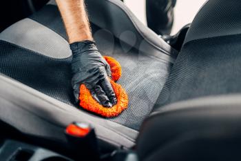 Professional chemical cleaning of car seats with spoonge. Carwash service, male worker in gloves using special agent