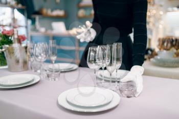 Waitress in gloves puts the tableware, table setting. Serving service, festive dinner decoration, holiday dinnerware