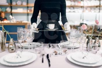Waitress with a tray puts the dishes, table setting. Serving service, festive dinner decoration, holiday dinnerware, tableware