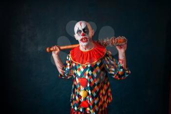 Crazy bloody clown with baseball bat. Man with makeup in halloween costume, maniac