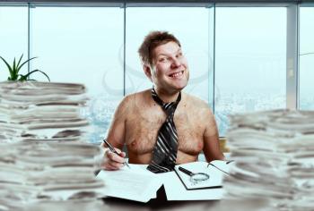 Crazy businessman in the tie on the naked body between stacks of paper in office. Mad businessperson works with documents, bad emotion, stress