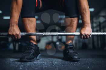 Male powerlifter prepares for deadlift a barbell in gym. Weightlifting workout, powerlifting training, lifter works with weight in sport club