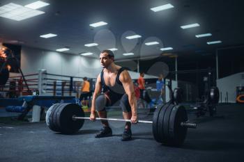 Male powerlifter starting deadlift a barbell in gym. Weightlifting workout, powerlifting training, lifter works with weight in sport club
