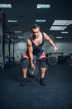 Strong man in sportswear doing exercise with kettlebell, weight lifting. Weightlifting workout, athlete in sport or fitness club, lifter on training in gym