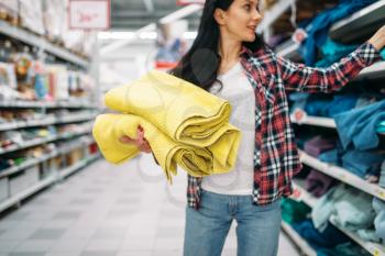 Young woman buying towels in supermarket. Female customer on  shopping in hypermarket, department of goods for the house