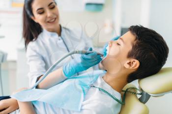 Caries removal procedure, pediatric dentistry, children stomatology. Female dentist drilling teeth, dental clinic