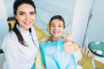 Female dentist and little boy in a dental chair shows thumbs up, pediatric dentistry, children stomatology