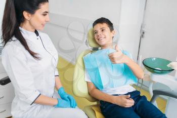 Female dentist and little boy in a dental chair shows thumbs up, pediatric dentistry, children stomatology
