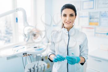 Smiling female dentist in uniform and gloves, dental clinic, professional pediatric dentistry, children stomatology