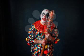 Mad bloody clown with baseball bat. Man with makeup in halloween costume, zombie