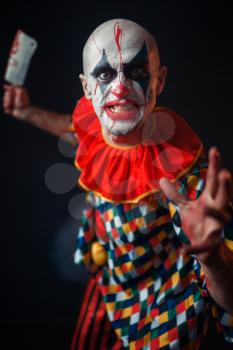Mad bloody clown with meat cleaver and baseball bat, circus horror. Man with makeup in carnival costume