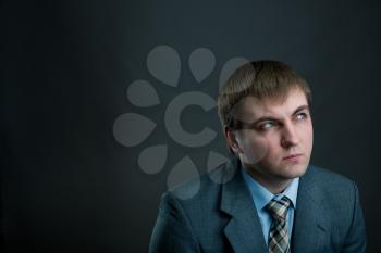 Young pensive businessman in suit and tie on black background. Thoughtful businessperson, male manager thinking