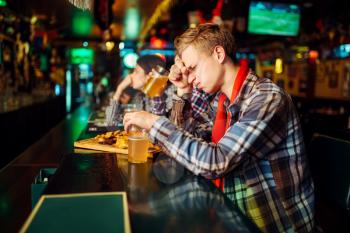 Sad football fan covers face with hands at the counter in sports bar. Tv broadcasting, favorite team loss
