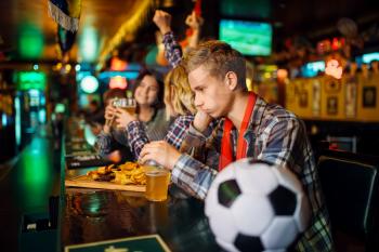 Upset football fan sitting at the counter in sports bar. Tv broadcasting, favorite team loss, game over
