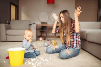 Little kid spilled popcorn on the floor, motherhood problems. Sad mom and son together at home, parenthood