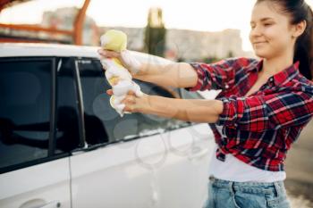 Female person with sponge scrubbing vehicle window with foam, car wash. Young woman on self-service automobile washing. Outdoor carwash