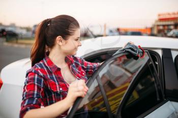 Woman wipes automobile after washing on self-service car wash. Lady cleaning vehicle