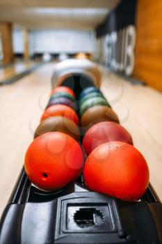 Color bowling balls in feeder, lane with pins on background, nobody. Bowling game concept