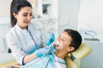 Seal installation process, pediatric dentistry, children stomatology. Female dentist drilling teeth, dental clinic