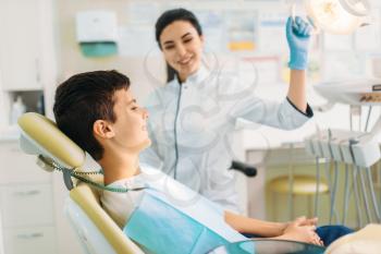 Boy in a dental clinic, pediatric dentistry. Female doctor examines the teeth of a small patient