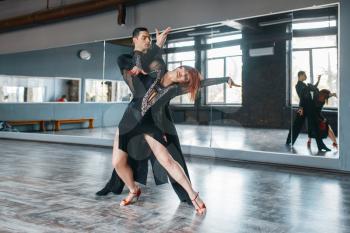 Two elegance dancers in costumes on ballrom dance training in class. Female and male partners on professional pair dancing in studio