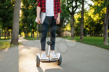Young man riding on mini gyro board in summer park. Outdoor recreation with electric gyroboard. Eco transport with balance technology, electrical gyroscope vehicle