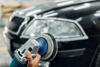 Auto detailing of car headlights on carwash service. Man working with polishing machine