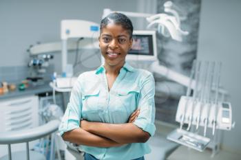 Smiling female patient in dental clinic, medical equipment on background. Woman in dentistry cabinet, stomatology, teeth care