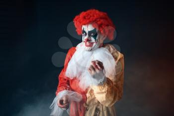 Portrait of scary bloody clown with crazy eyes. Man with makeup in carnival costume, mad maniac