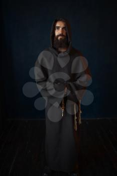 Monk in black robe with hood, religion. Mysterious friar in dark cape