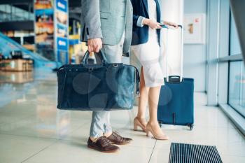 Male and female passengers with luggage in airport, business trip. Businessman and businesswoman in air terminal, negotiation travel