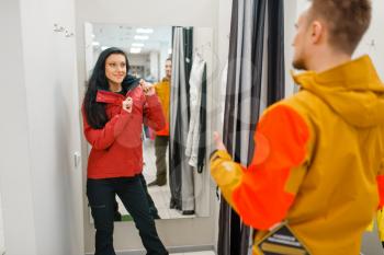 Couple trying on jackets for ski or snowboarding, sports shop. Winter season extreme lifestyle, active leisure store, customers with protect equipment