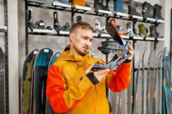 Man choosing ski boot fastening, shopping in sports shop. Winter season extreme lifestyle, active leisure store, customer buying skiing equipment