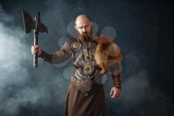 Angry viking with axe, martial spirit, barbarian image. Ancient warrior in smoke
