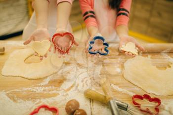Two little girls chefs holding the cookie cutters, bakery preparation on the kitchen, funny bakers. Kids cooking pastry and having fun, children cooks preparing cake