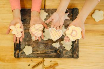 Two little girls cooks hands holds cookies over wooden board, bakery preparation on the kitchen, funny bakers. Kids cooking pastry, children chefs preparing cake