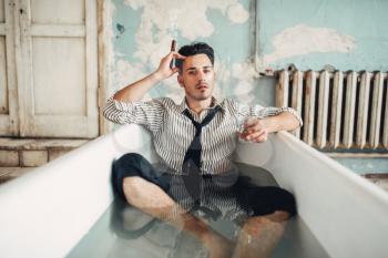 Drunk businessman smoke cigar in bathtub, suicide man concept. Problem in business, stress
